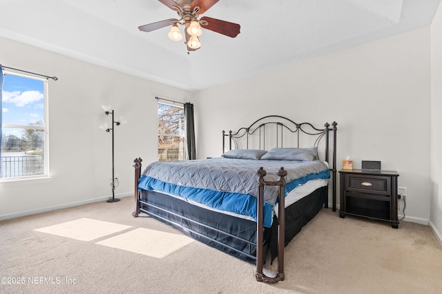 bedroom featuring light carpet, a tray ceiling, and multiple windows