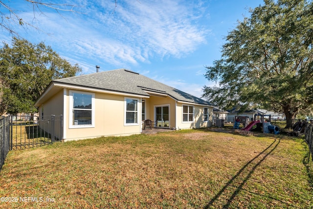 rear view of house featuring a yard, a shingled roof, and a fenced backyard