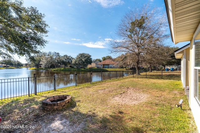 view of yard with a fire pit, a water view, and a fenced backyard