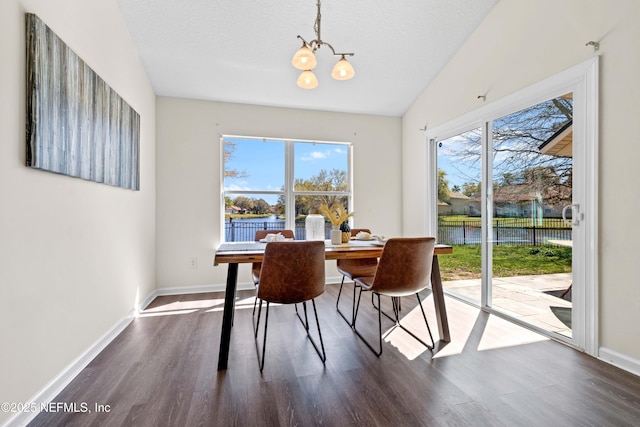 dining room featuring baseboards, a water view, an inviting chandelier, and dark wood-style flooring