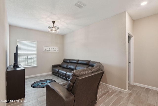 living room featuring wood tiled floor, visible vents, and baseboards