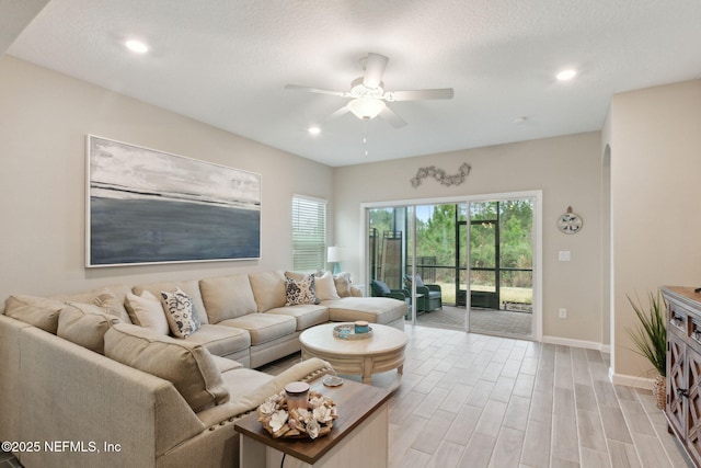 living room with baseboards, a ceiling fan, a textured ceiling, light wood-style floors, and recessed lighting