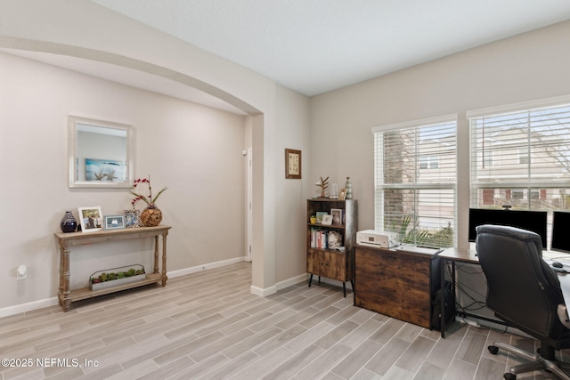 office area featuring arched walkways, wood tiled floor, and baseboards