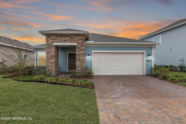 view of front of home with decorative driveway, a front yard, stone siding, and an attached garage