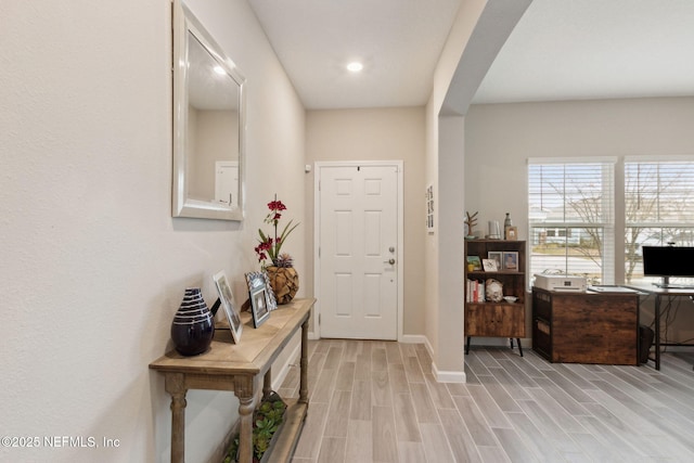 foyer entrance featuring arched walkways, wood finish floors, and baseboards