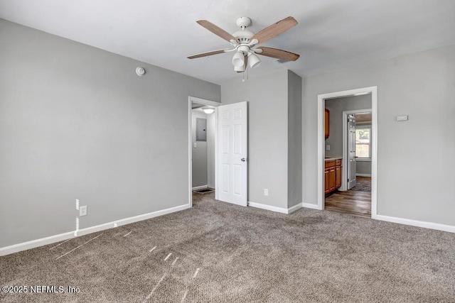 unfurnished bedroom with ceiling fan, ensuite bathroom, and dark carpet