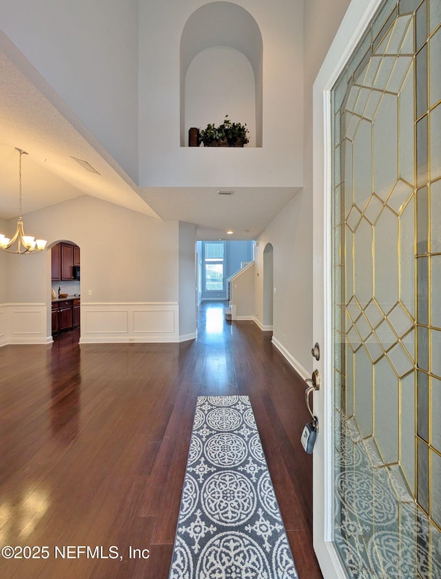 foyer entrance featuring dark hardwood / wood-style flooring, vaulted ceiling, and a notable chandelier