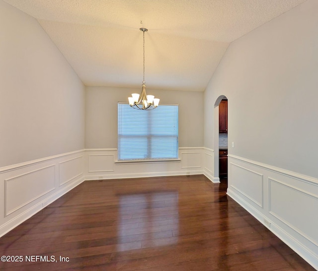 unfurnished dining area featuring a chandelier, a textured ceiling, dark hardwood / wood-style floors, and vaulted ceiling