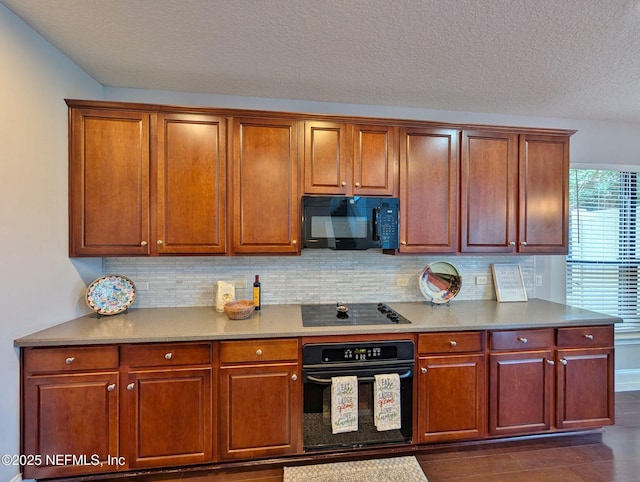 kitchen featuring backsplash, dark hardwood / wood-style flooring, black appliances, and a textured ceiling