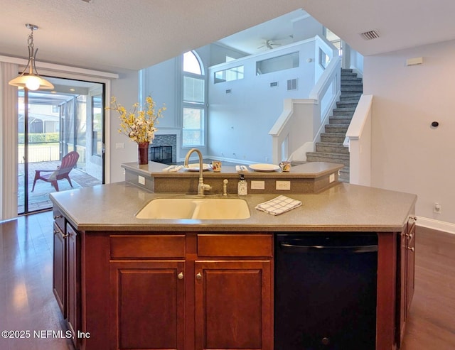 kitchen with dark hardwood / wood-style flooring, black dishwasher, a kitchen island with sink, and sink