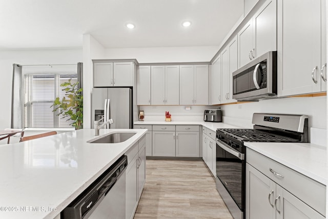 kitchen featuring gray cabinetry, sink, light wood-type flooring, and appliances with stainless steel finishes