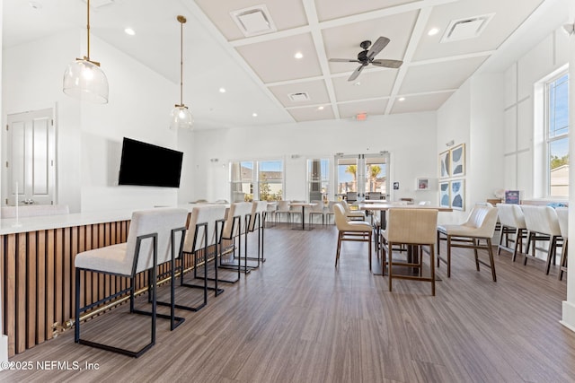 dining room with hardwood / wood-style flooring, ceiling fan, a high ceiling, and coffered ceiling