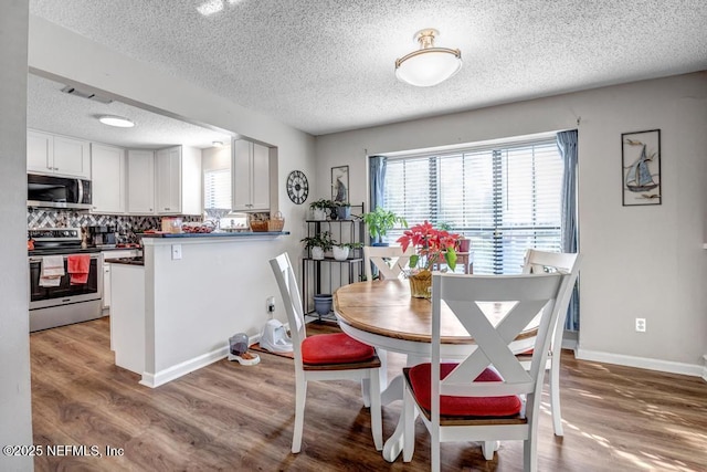 dining area featuring a textured ceiling and light hardwood / wood-style flooring