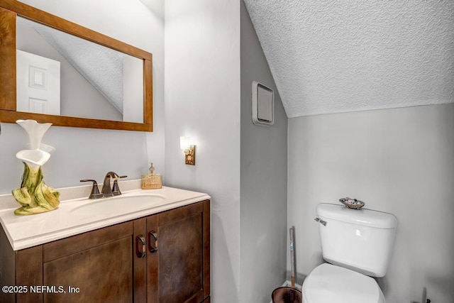 bathroom featuring a textured ceiling, vanity, vaulted ceiling, and toilet