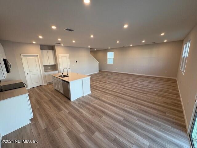 kitchen with sink, stainless steel dishwasher, light hardwood / wood-style floors, a center island with sink, and white cabinets