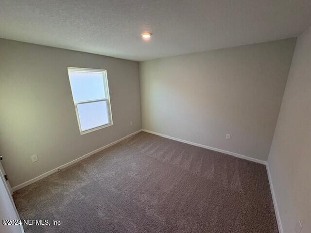 empty room featuring dark carpet and a textured ceiling