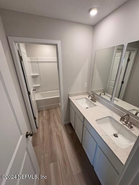 bathroom featuring bathing tub / shower combination, vanity, a textured ceiling, and hardwood / wood-style flooring