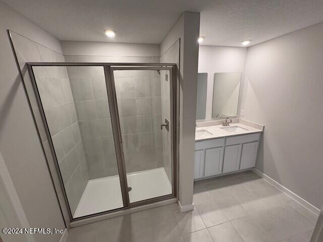 bathroom with tile patterned floors, vanity, and a shower with shower door