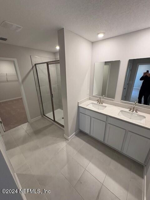 bathroom with tile patterned floors, vanity, an enclosed shower, and a textured ceiling