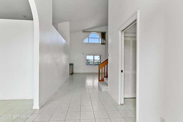 hallway featuring light tile patterned floors and vaulted ceiling