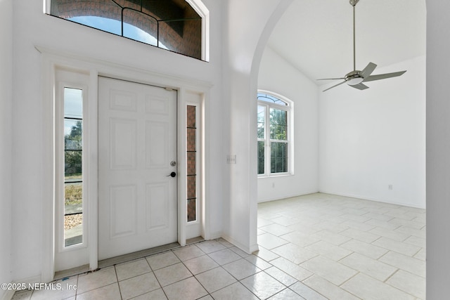 entryway with ceiling fan, light tile patterned flooring, and lofted ceiling