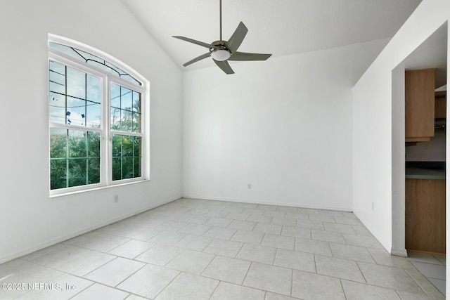 empty room with ceiling fan, light tile patterned flooring, and lofted ceiling