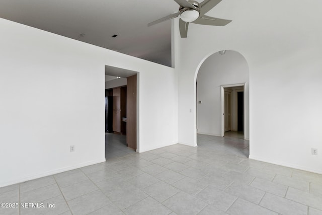 unfurnished room with ceiling fan, a towering ceiling, and light tile patterned floors