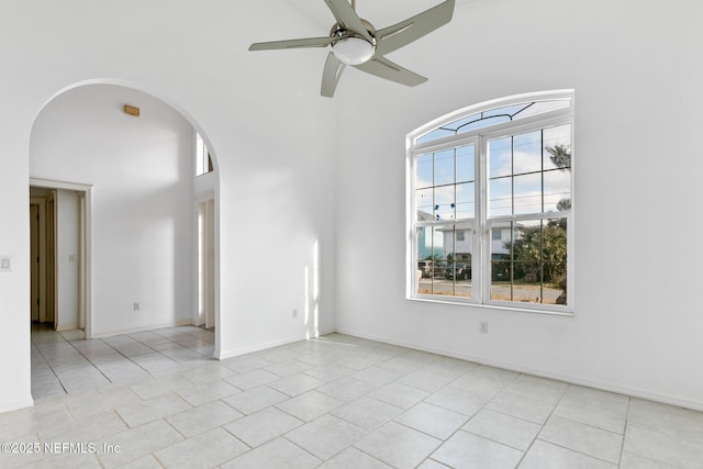 spare room featuring ceiling fan, light tile patterned floors, and a high ceiling