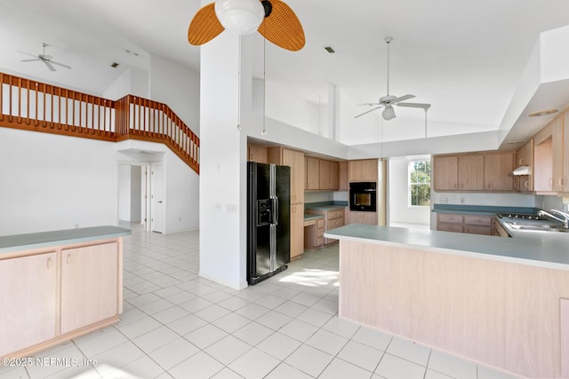 kitchen with black appliances, light brown cabinets, kitchen peninsula, and high vaulted ceiling