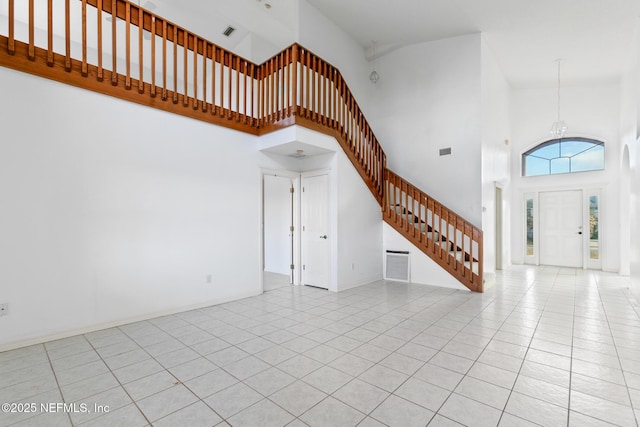 unfurnished living room with light tile patterned floors, a high ceiling, and a chandelier