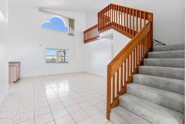 staircase with a high ceiling and tile patterned floors