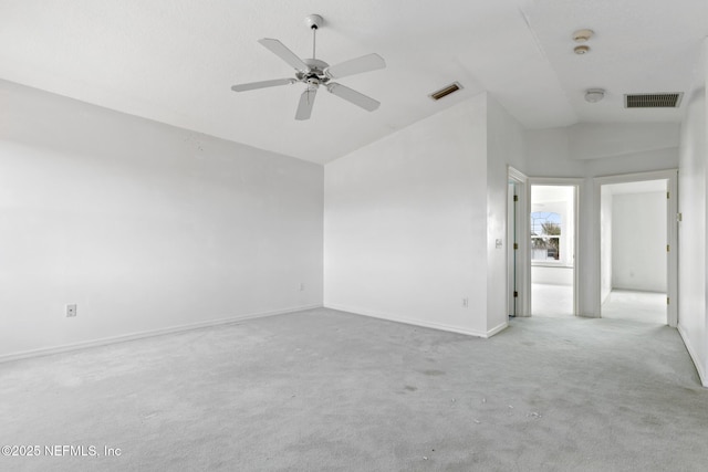 empty room featuring light carpet, ceiling fan, and vaulted ceiling