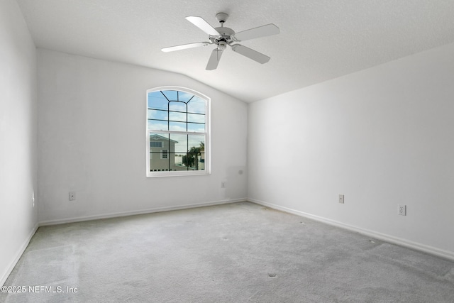 spare room with light colored carpet, vaulted ceiling, and ceiling fan