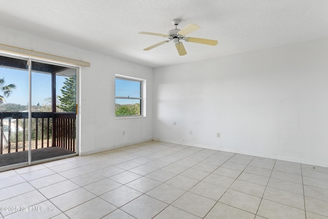 empty room with a textured ceiling, ceiling fan, and light tile patterned flooring