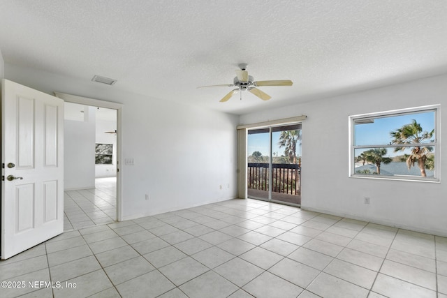 tiled empty room with ceiling fan and a textured ceiling