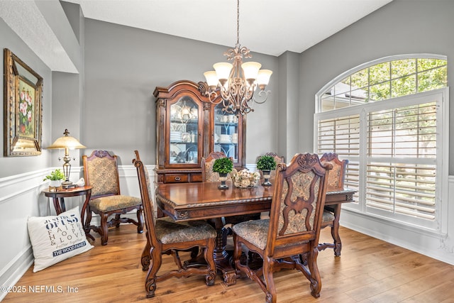 dining space with light hardwood / wood-style floors and a chandelier