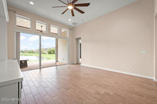 unfurnished living room with ceiling fan and a water view