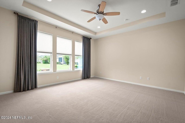 carpeted empty room featuring ceiling fan and a tray ceiling