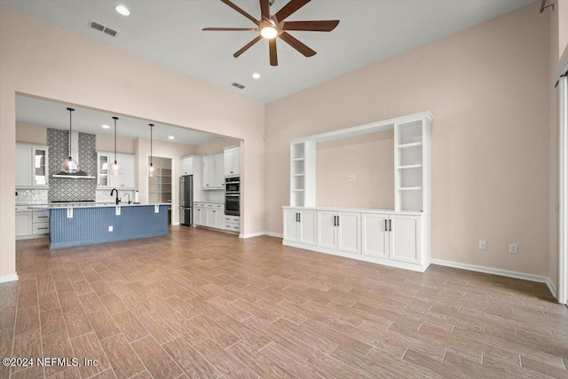 unfurnished living room with ceiling fan and sink