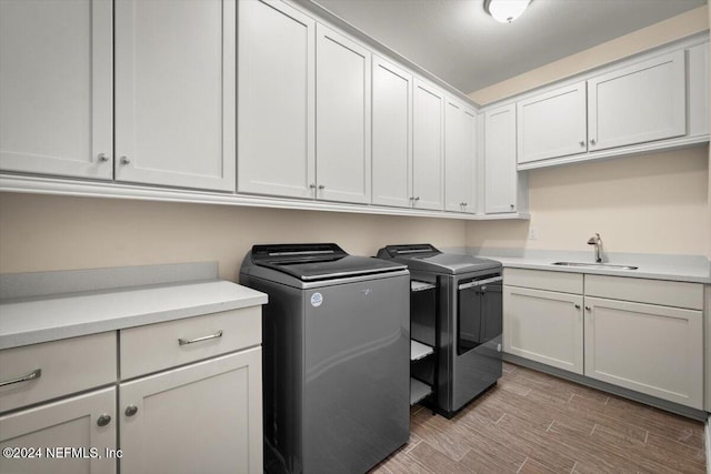 laundry area featuring washer and clothes dryer, cabinets, and sink