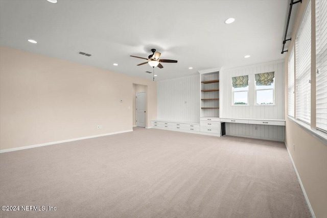 unfurnished living room with light colored carpet and ceiling fan