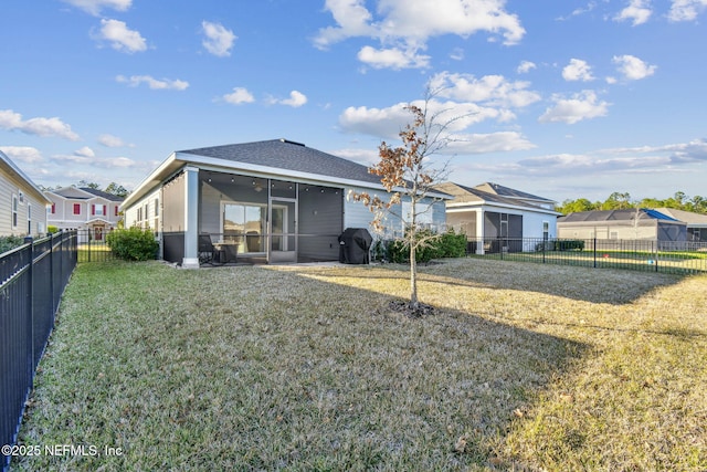 rear view of house featuring a yard and a sunroom