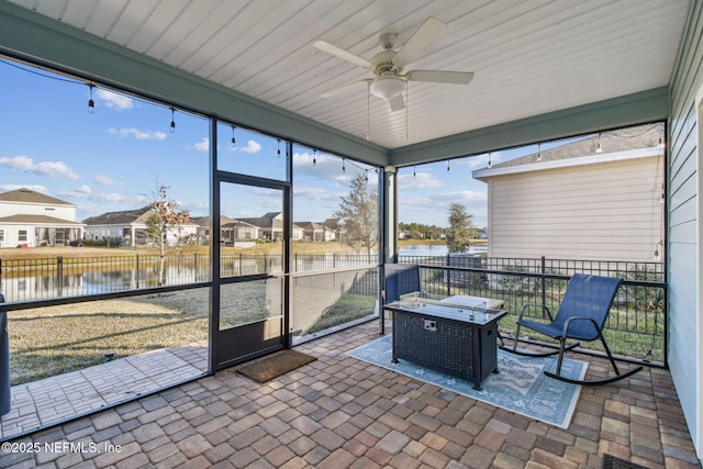 sunroom / solarium featuring plenty of natural light, ceiling fan, and a water view