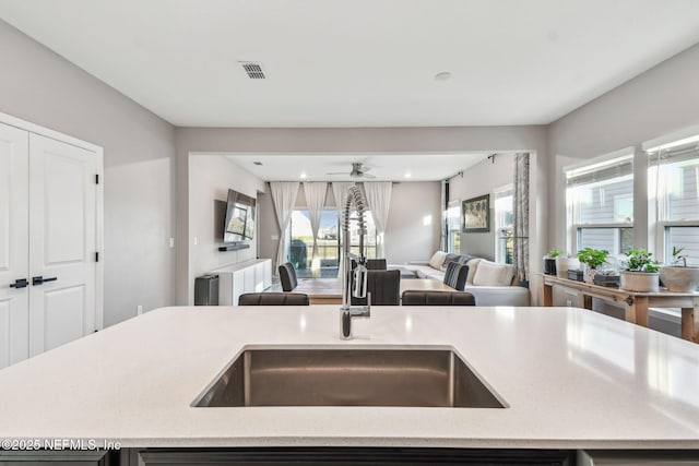 kitchen with ceiling fan, sink, and a center island with sink