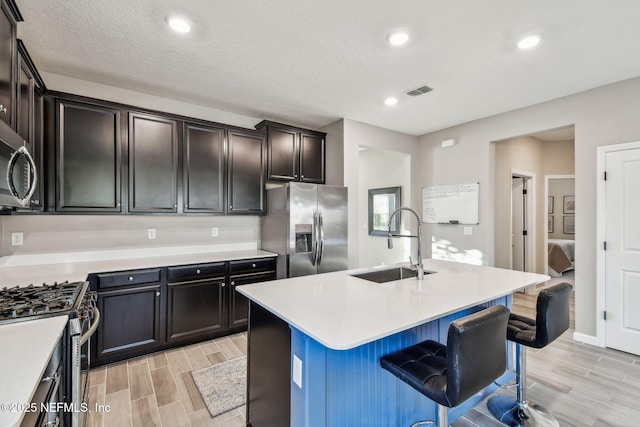 kitchen featuring sink, a kitchen breakfast bar, a kitchen island with sink, dark brown cabinetry, and stainless steel appliances