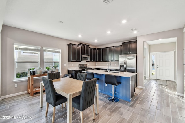 kitchen featuring sink, a center island with sink, a breakfast bar area, and appliances with stainless steel finishes