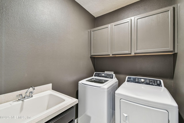 clothes washing area featuring washer and dryer, sink, and cabinets