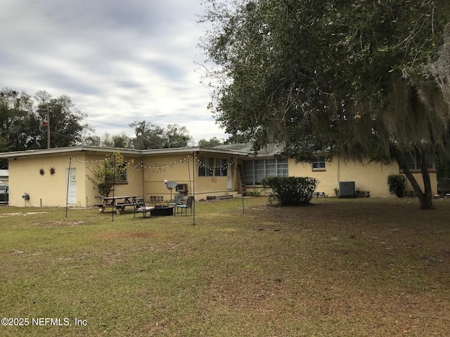 back of house with central AC and a lawn