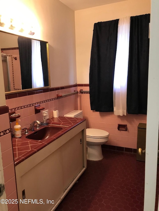 bathroom with tile patterned floors, vanity, tile walls, and toilet