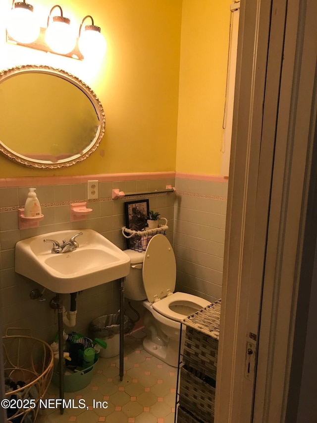 bathroom featuring tile patterned floors, sink, tile walls, and toilet